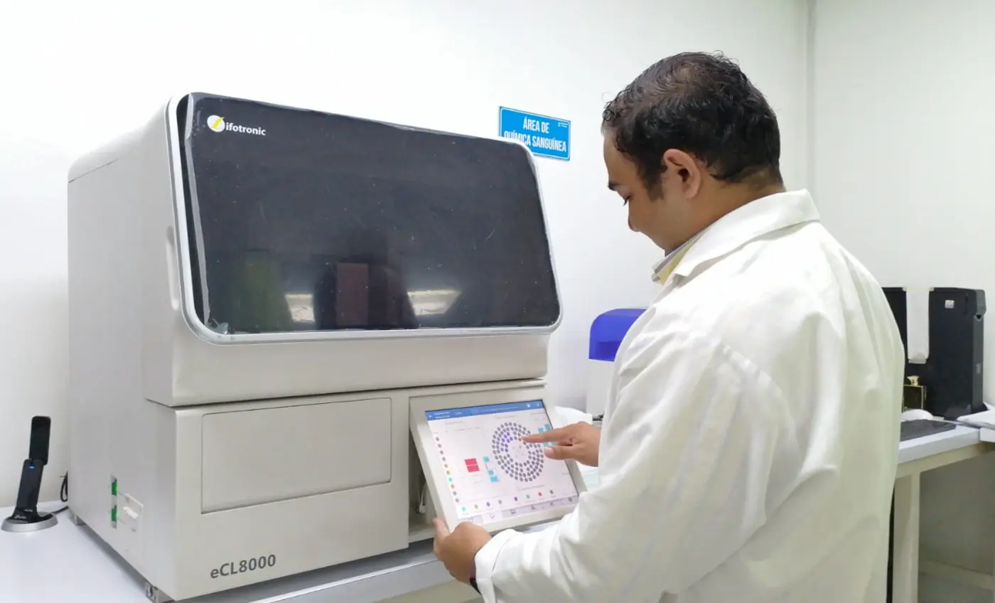 Profesional de Laboratorios Fleming operando un analizador automatizado